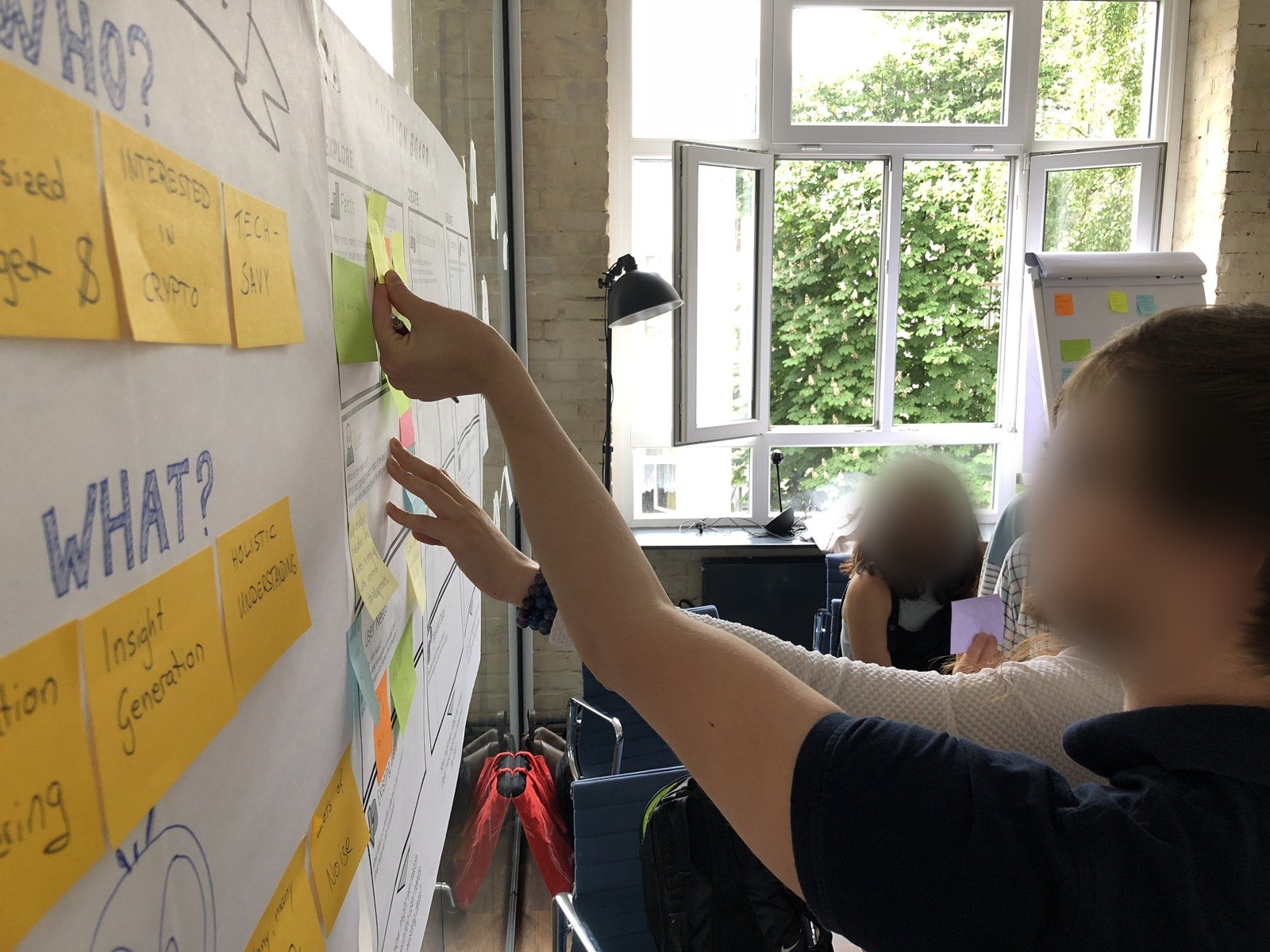 Workshop participants placing sticky notes on the Data Innovation Board next to an empathy map