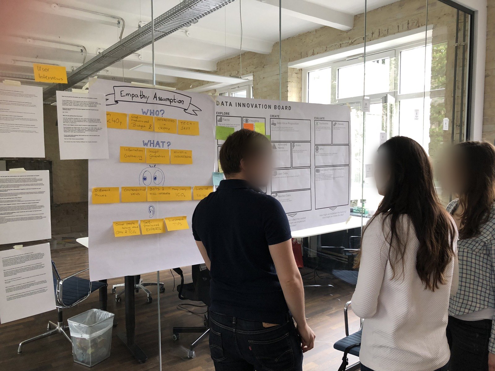 Three workshop participants discussing in front of the empathy map and the Data Innovation Board